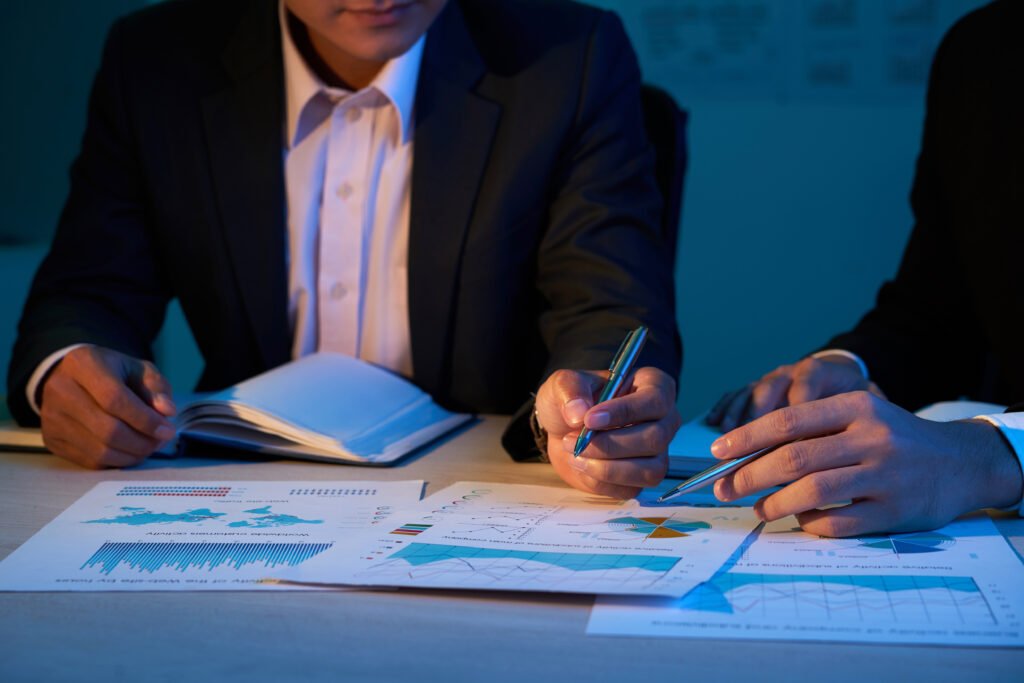 Business professional reviewing financial reports and charts during due diligence for a business sale