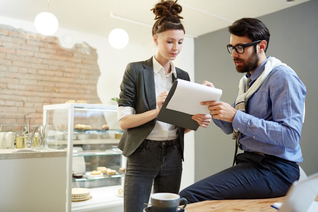 Two business professionals reviewing documents and discussing a potential business transaction.